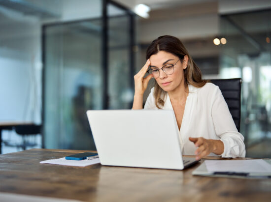 Worried fatigued mature business woman wearing glasses having headache at work.